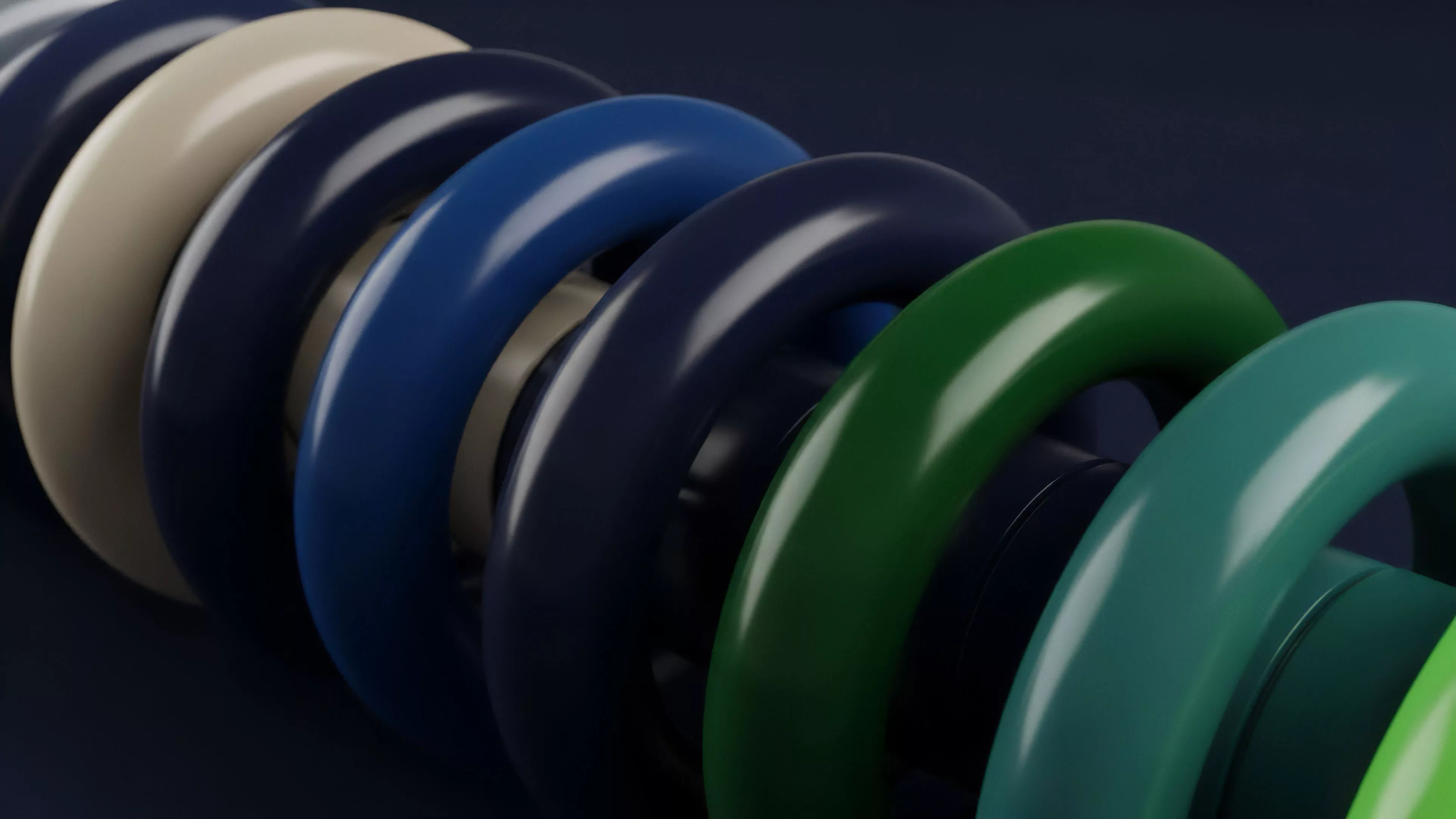 A close-up view of a sequence of glossy, interconnected rings, transitioning in color from light beige to deep blue, then to dark green and teal.